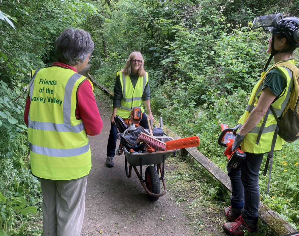 Friends of the Loxley Valley volunteers with a wheelbarrow of tools on the "easy access" footpath near Olive Mill